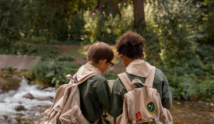 two boy scouts looking at a map in the forest