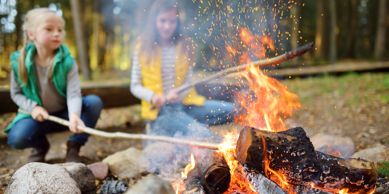 two kids roasting marshmallows in front of a camp fire