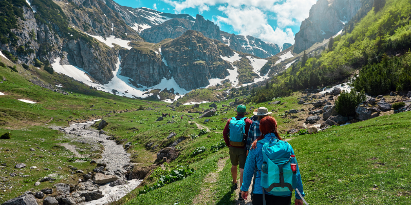 three adults hiking on the side of a mountain