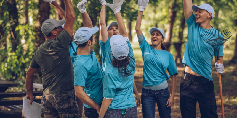 a group of men and women volunteers raising their hands in a park