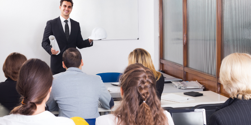 man standing talking to a group of students